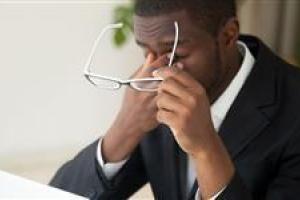 man-rubbing-eyes-holding-glasses-in-front-of-computer-big-spotlight-size