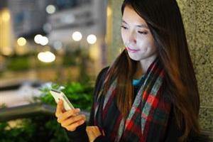 woman-looking-at-smartphone-outside-at-night-in-a-city-spotlight